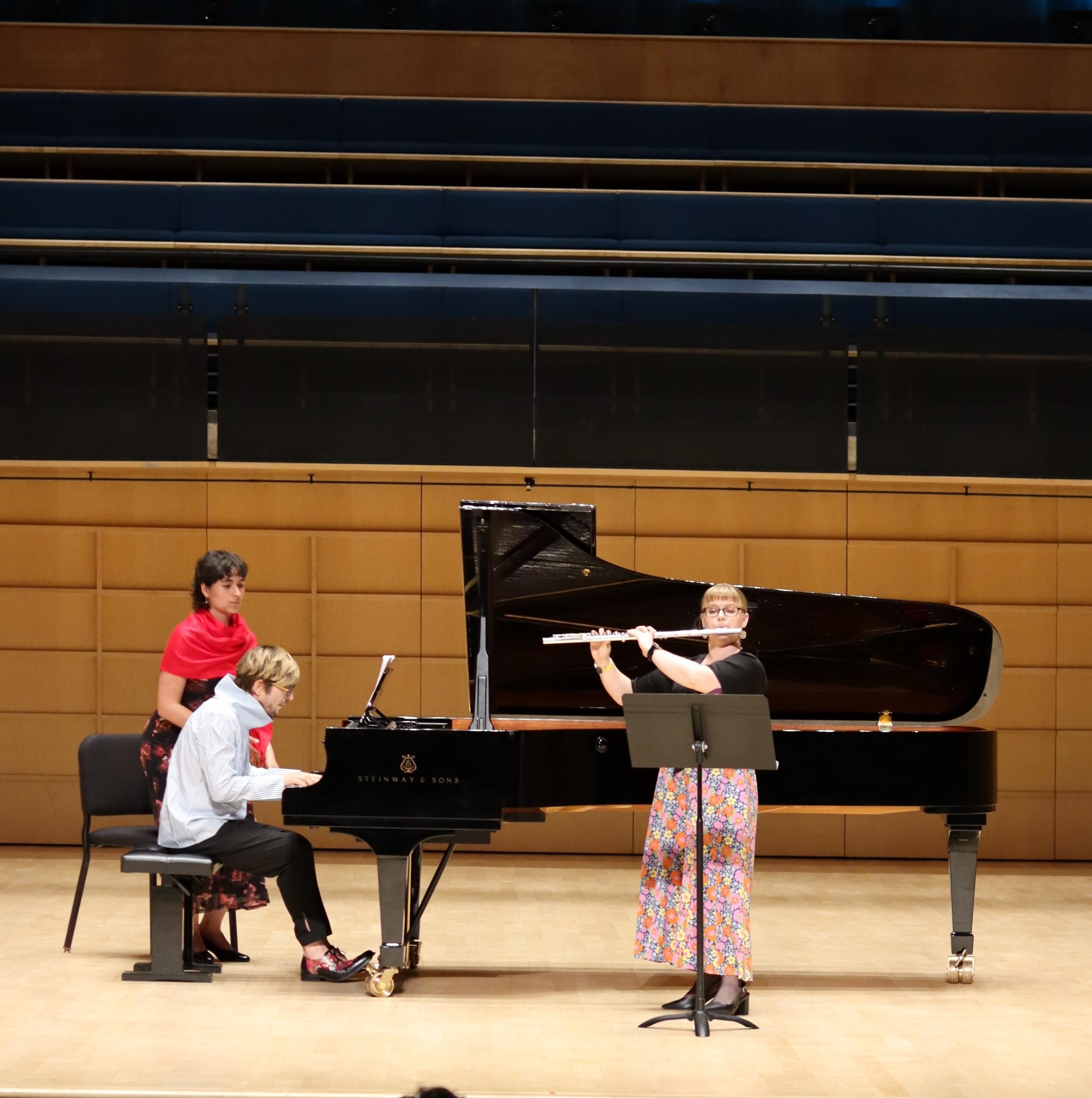 Flautist and pianist performing on a stage.
