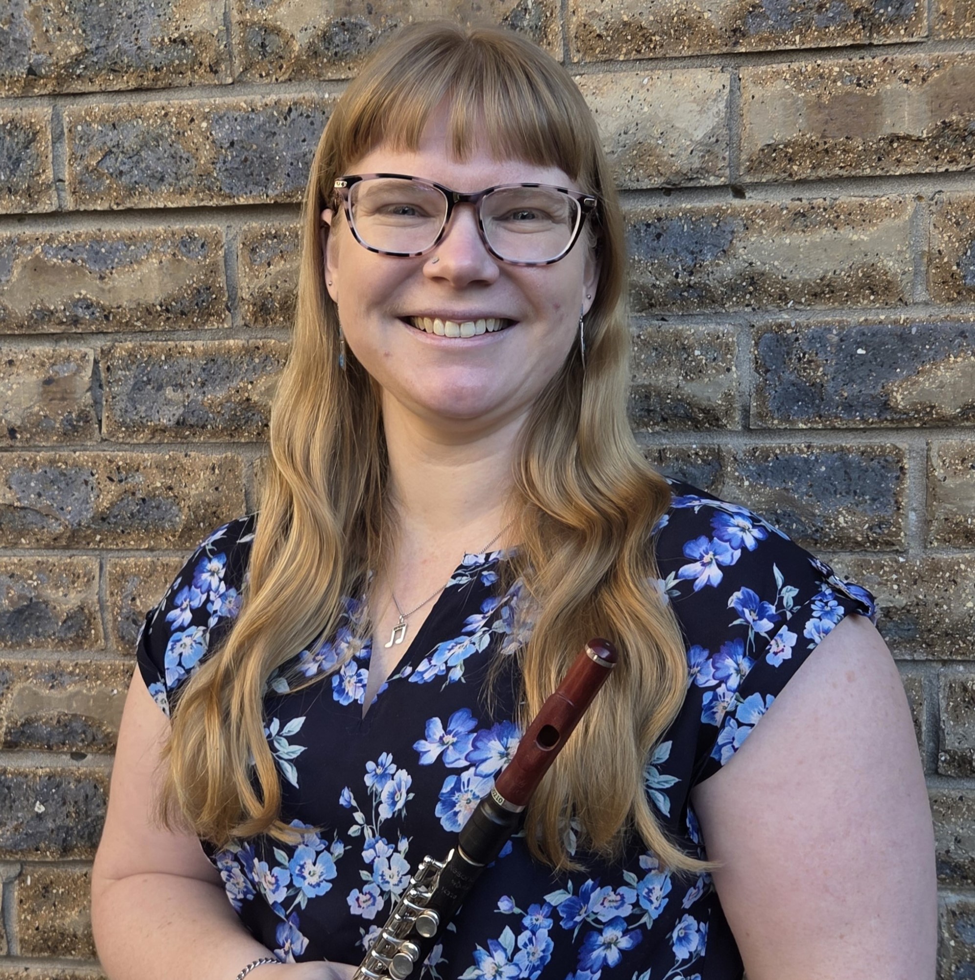 A smiling woman holding a piccolo.
